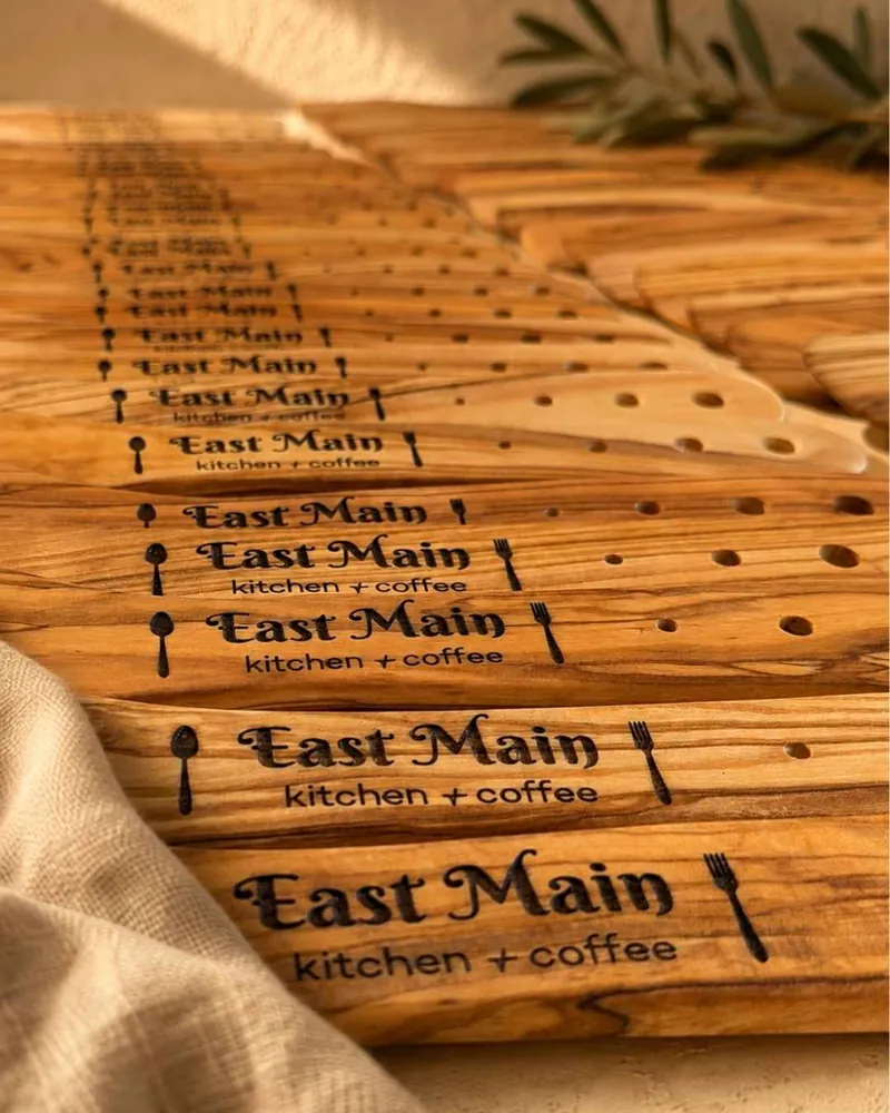 Stack of olive wood spatulas laser-engraved with the East Main kitchen + coffee logo