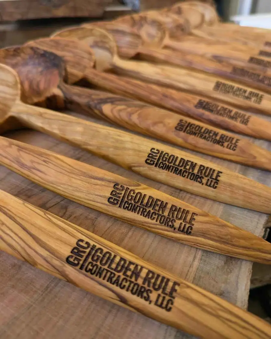 Close-up of olive wood serving utensils laser-engraved for Golden Rule Contractors