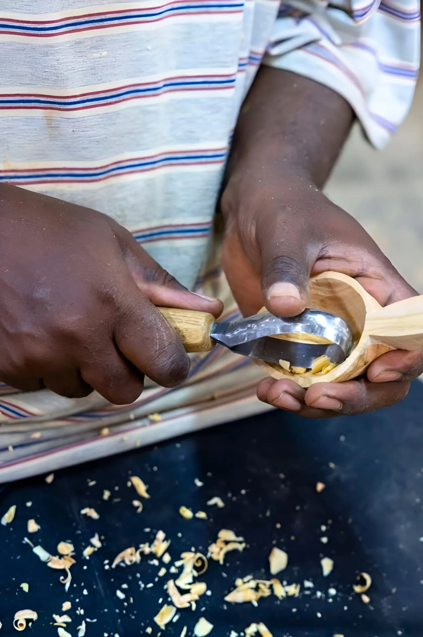 An artisan refining the back of a spoon with a hand plane