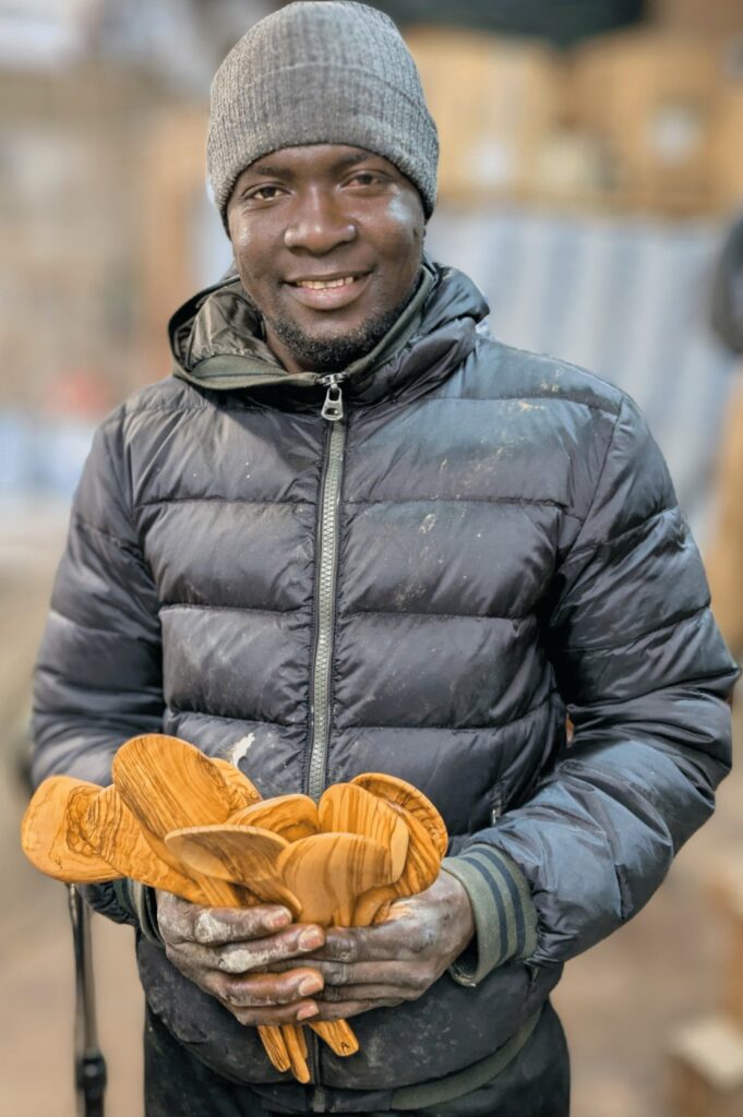 "Refugee artisan in Greece, carefully hand-carving an olive wood utensil."